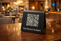 Placa QR Code em acrílico preto personalizada para hotel com menu digital sobre balcão de receção